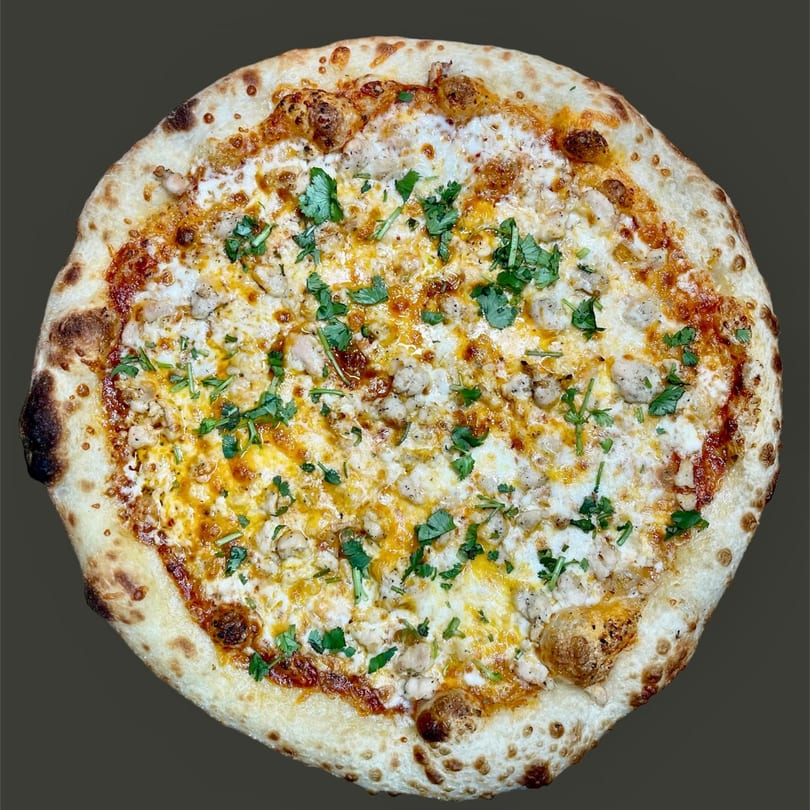 Chicken pizza with melted white and yellow cheese, fresh cilantro, and a golden crust.